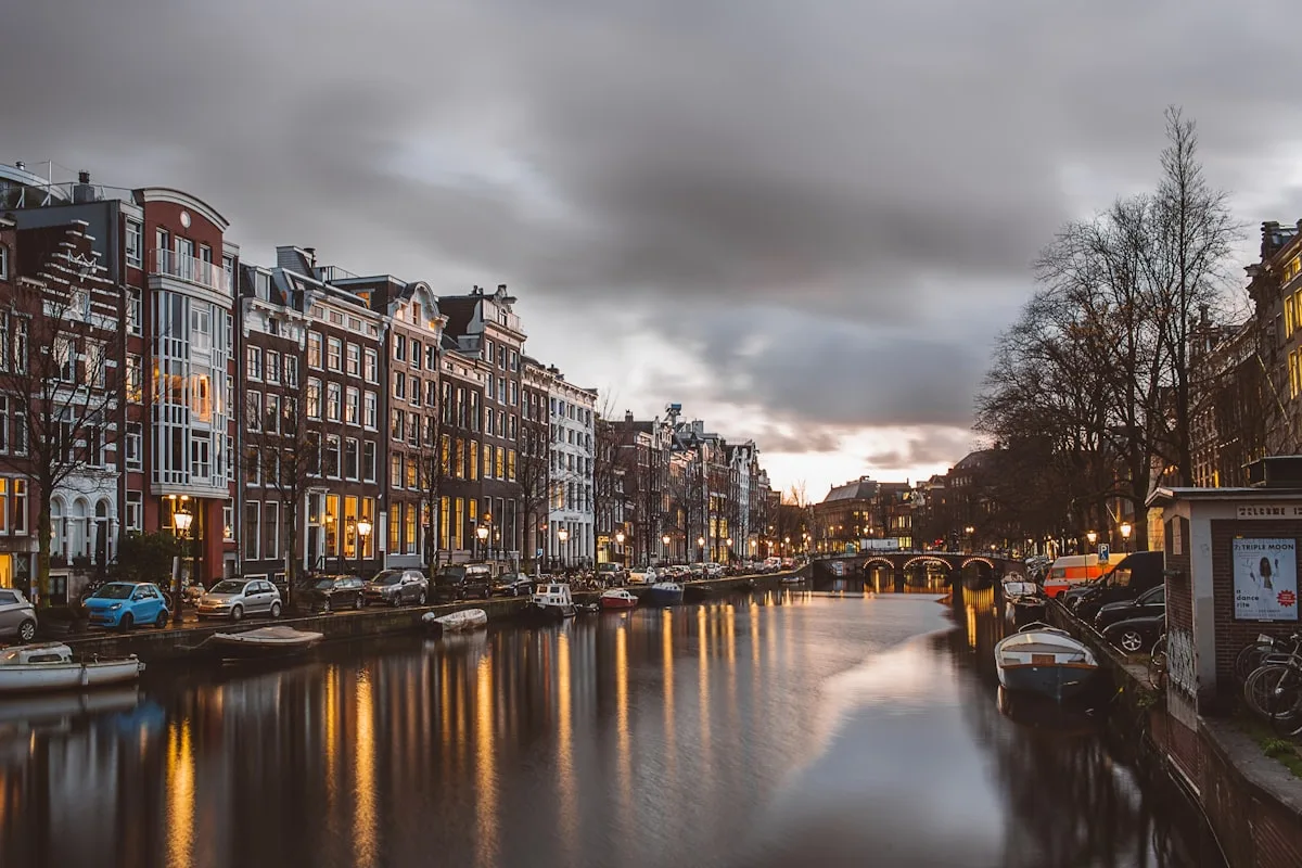 Amsterdam canal-side street with bicycles and traditional Dutch facades, illustrative backdrop for the city's May 1 ban on meat and fossil-fuel advertising in public spaces