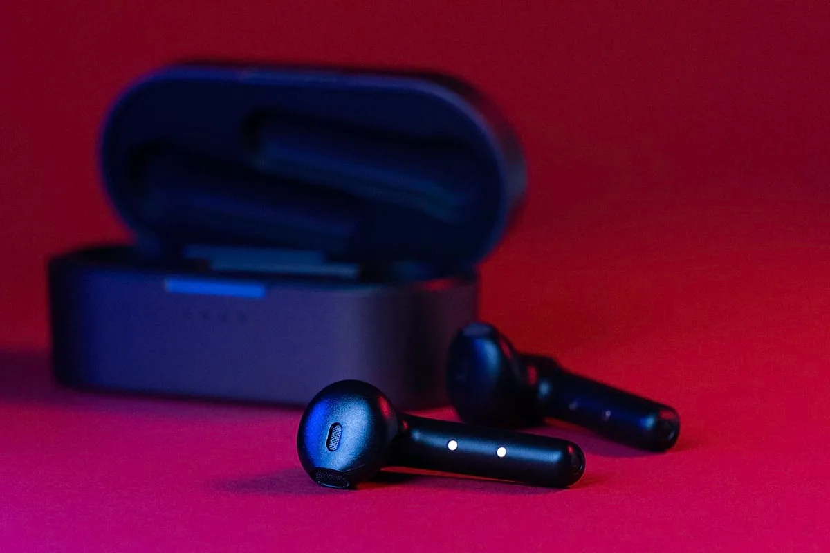 White wireless earbuds in charging case, illustrative of AirPods-style hardware (not the rumored camera model)