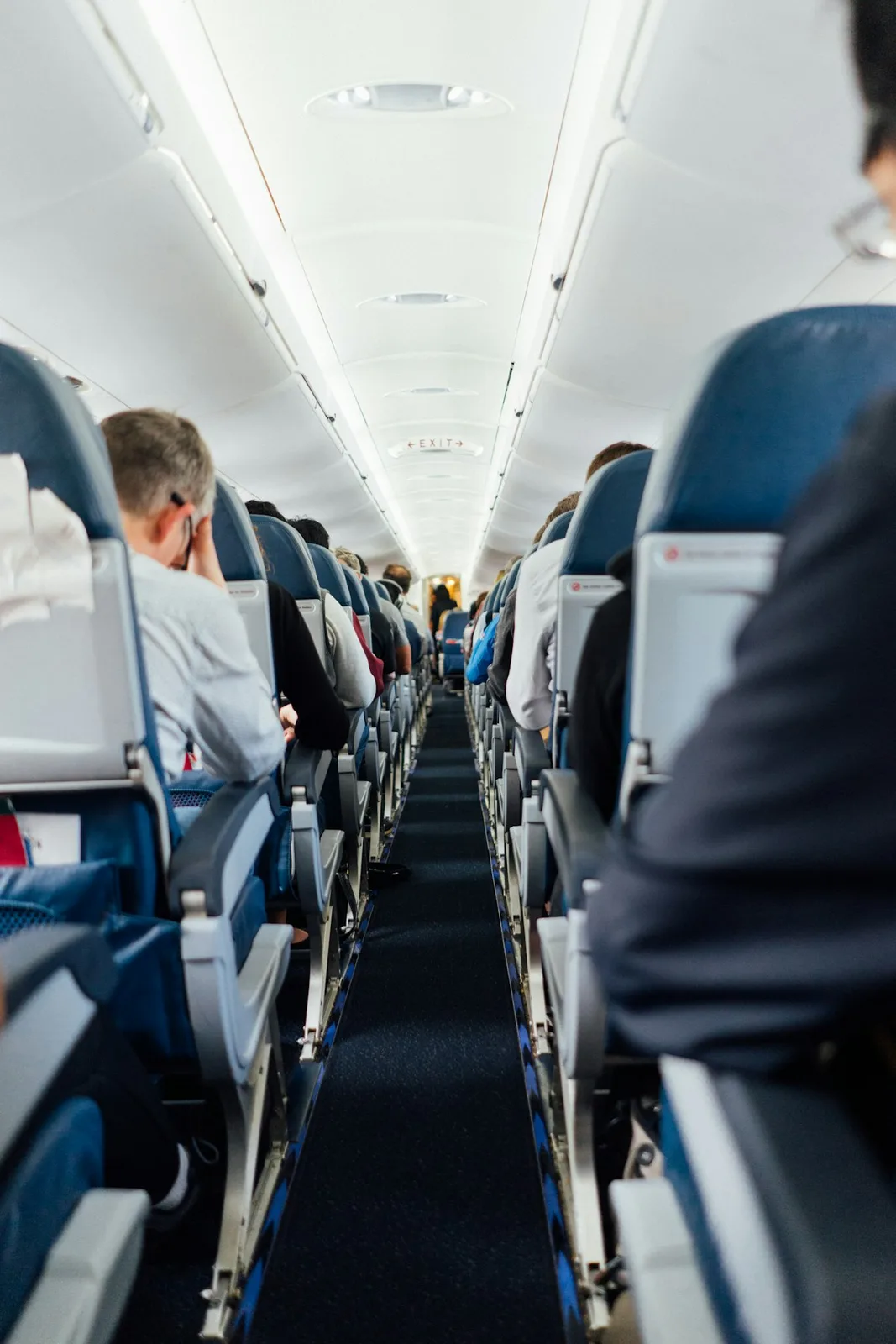 Interior aisle of a wide-body passenger jet showing seat rows, overhead bins and lavatory doors in low cabin lighting — illustrative imagery for Newsorga's coverage of the Uxbridge Magistrates' Court conviction of Louis Gaston for vaping in the lavatory of British Airways flight BA172 from New York JFK to London Heathrow on November 23, 2025 and assaulting American passenger Laurel Dillon during the post-landing wait on the tarmac.