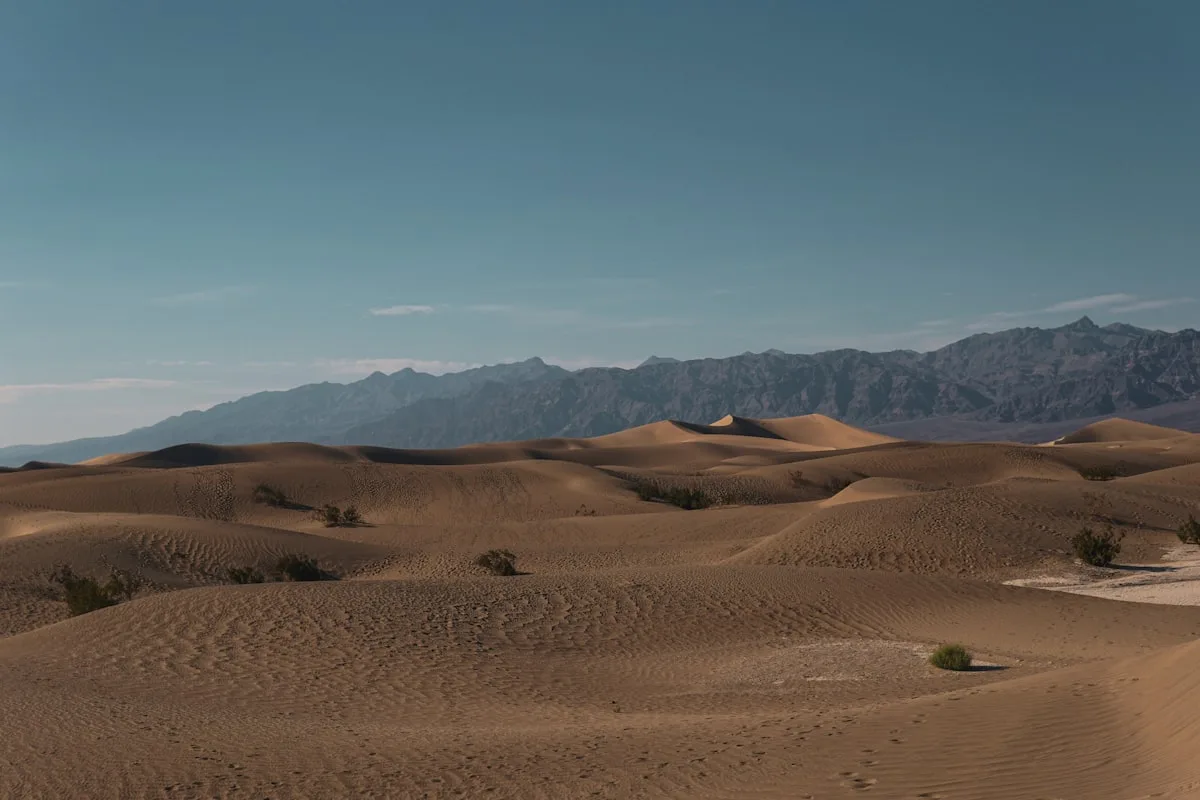 Stark desert landscape with distant ridgelines under a hot, hazy sky — illustrative imagery of the arid Mojave/Death Valley type terrain across which the National Weather Service's May 10-12, 2026 extreme-heat warnings have been issued, with Death Valley forecast to hit 111°F on Monday.