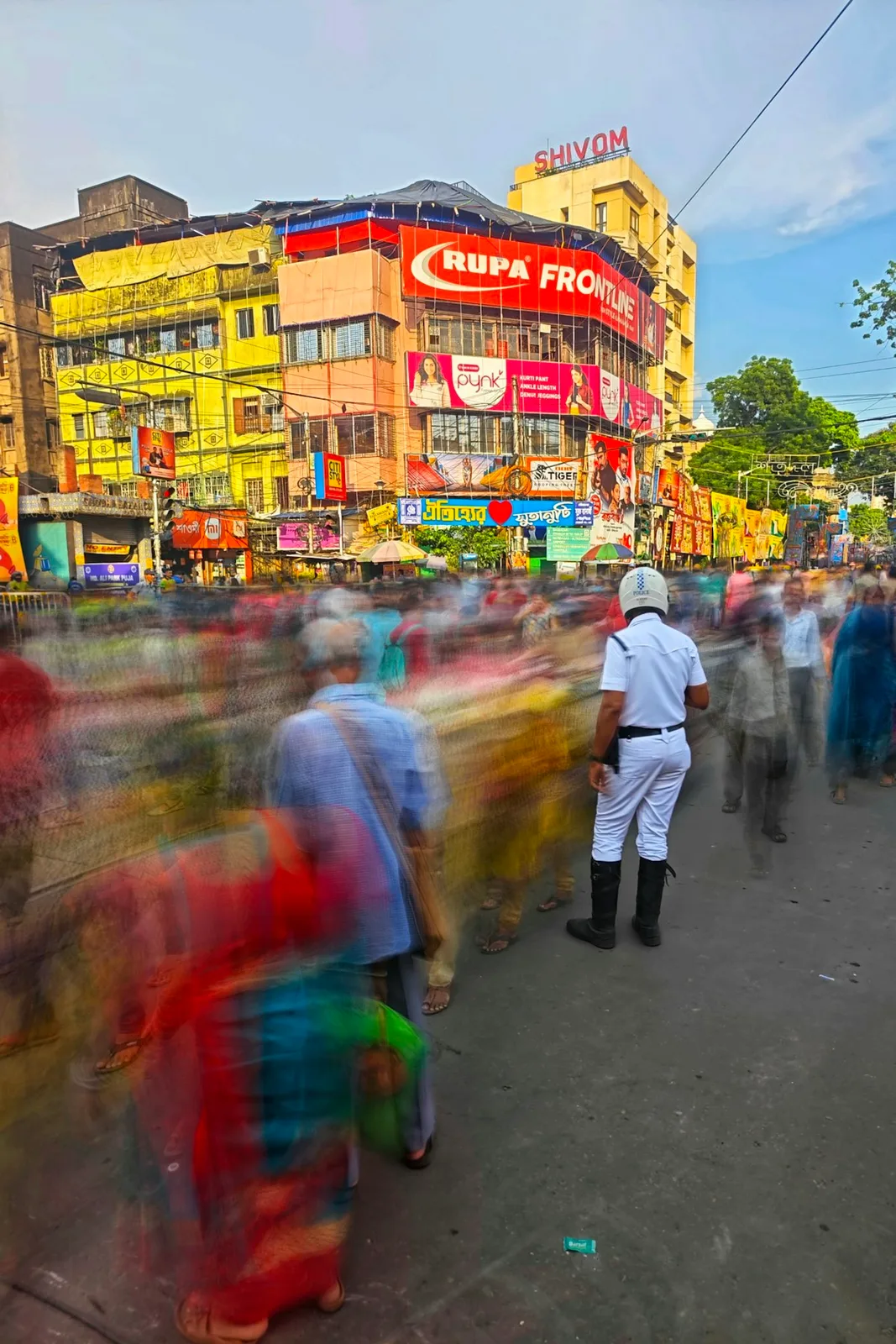 Crowd movement with a police officer on a busy Kolkata-area street