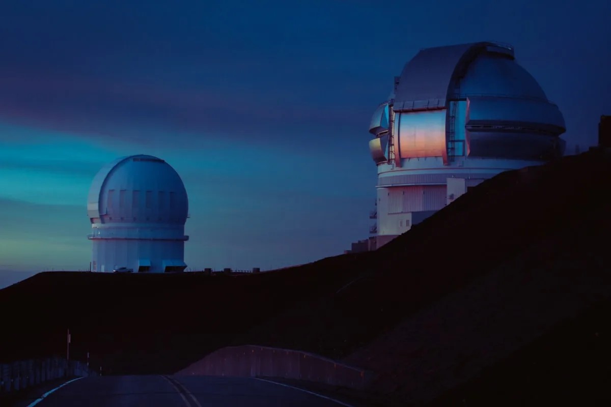 White-domed astronomical observatory on a mountain ridge under a clear sky — illustrative imagery of the kind of ground-based stellar-occultation observing site that the NAOJ-led Japanese network used on January 10, 2024 to detect a thin atmosphere on the trans-Neptunian object (612533) 2002 XV93.
