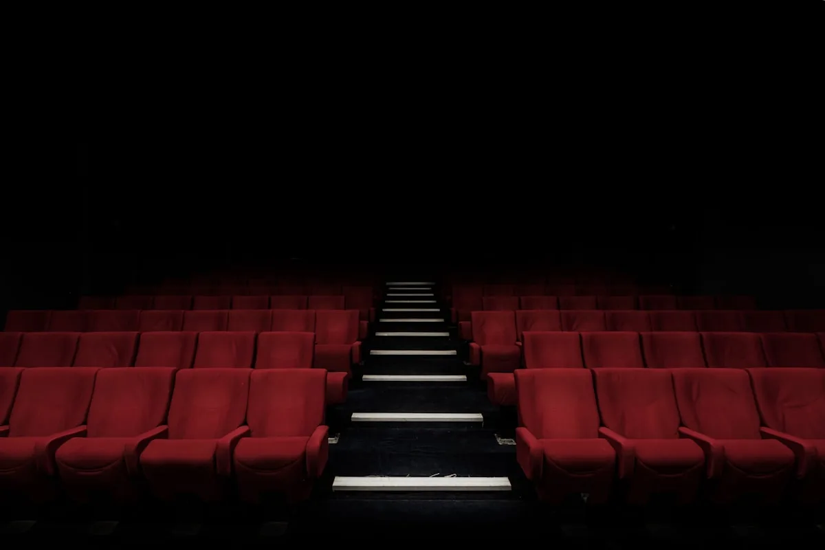 Darkened cinema auditorium rows—editorial metaphor for biopic release debates; not film stills or likeness from Michael