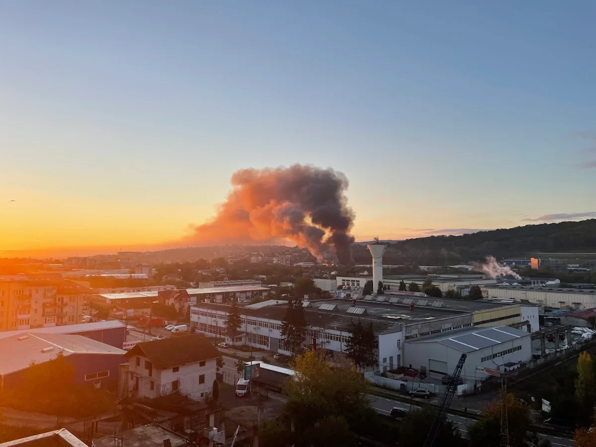 Heavy black smoke billows from a factory building under a hazy sky — illustrative imagery for the May 8, 2026 fire that destroyed three buildings at the Sigma Renew 360 polyethylene-pellet plant in Henry, Tennessee, where all eight employees were evacuated safely